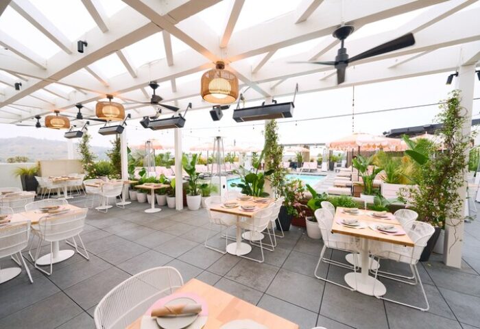 The Shay, A Destination By Hyatt Hotel's rooftop terrace. Gay-friendly hotel with tables, chairs, plants, and a pool view. Upscale dining.