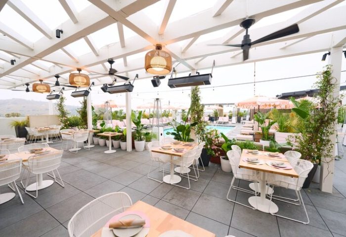 The Shay, A Destination By Hyatt Hotel's rooftop terrace. Gay-friendly hotel with tables, chairs, plants, and a pool view. Upscale dining.