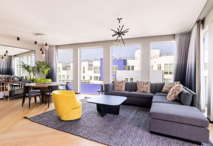 The Shay, A Destination By Hyatt Hotel: Modern suite with dining area, gray sectional, and yellow chair. Gay-friendly hotel for discerning travelers.