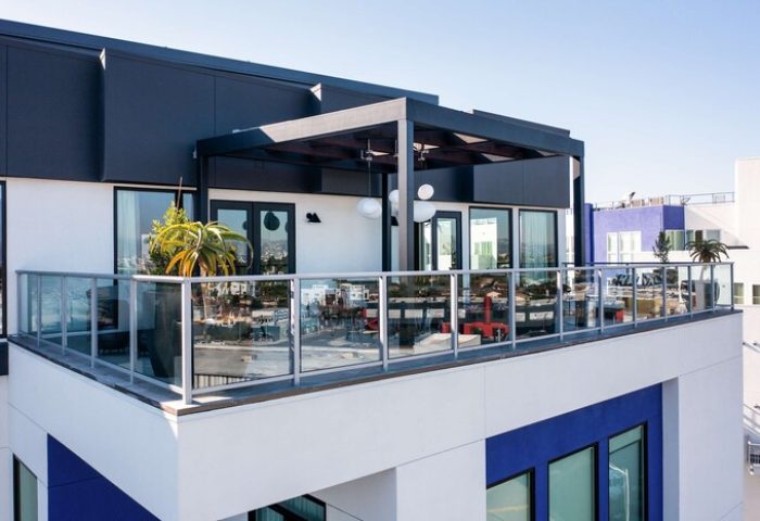 The Shay, a Destination by Hyatt hotel. Modern gay-friendly hotel balcony with glass railings, pergola, and city views. Stylish travel for gay men.