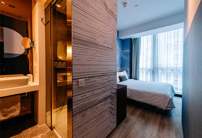 The Sheung Wan gay-friendly hotel room. Modern interior with bathroom, shower, and bedroom with a large window. Stylish design for gay travelers.