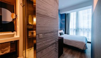 The Sheung Wan gay-friendly hotel room. Modern interior with bathroom, shower, and bedroom with a large window. Stylish design for gay travelers.