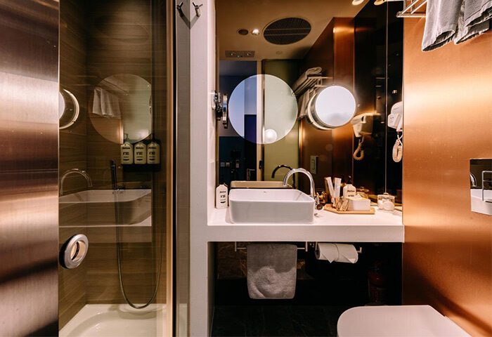 Bathroom interior at The Sheung Wan, a gay-friendly hotel. Features a modern sink, shower, and copper accents. Great for gay travel in Hong Kong.