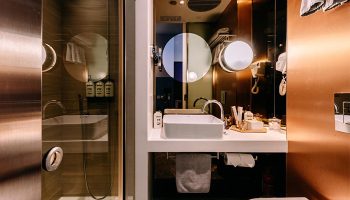 Bathroom interior at The Sheung Wan, a gay-friendly hotel. Features a modern sink, shower, and copper accents. Great for gay travel in Hong Kong.