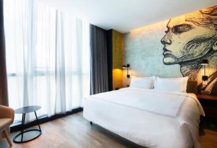 The Sheung Wan gay-friendly hotel room. Modern design with a bed, chair, and a face mural on the wall. Great for gay travelers in Hong Kong.
