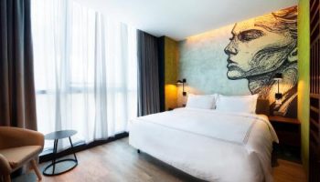 The Sheung Wan gay-friendly hotel room. Modern design with a bed, chair, and a face mural on the wall. Great for gay travelers in Hong Kong.