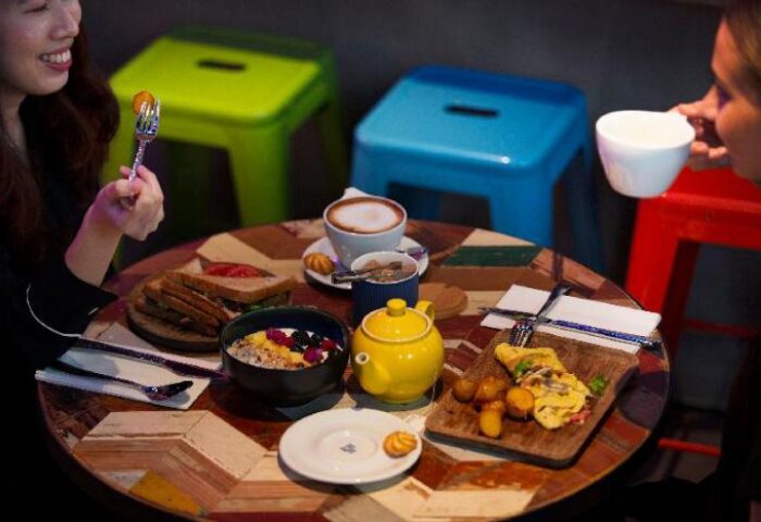 Breakfast at The Sheung Wan, a gay-friendly hotel in Hong Kong. Table with coffee, tea, sandwiches, and omelet. Enjoying a meal.
