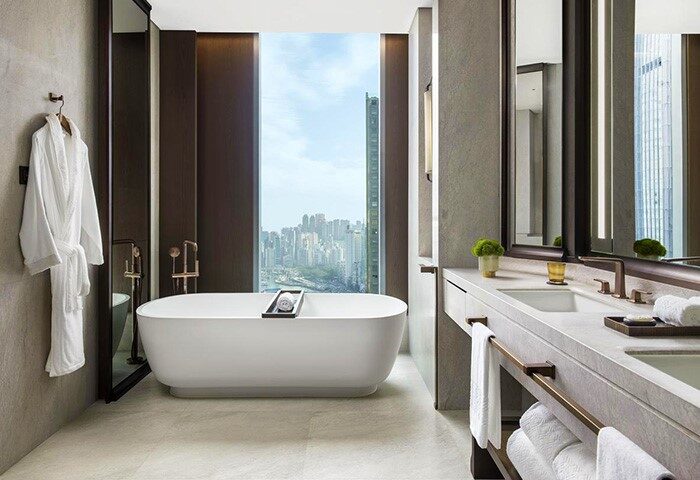 Bathroom at The St. Regis Hong Kong, a gay-friendly hotel. Features a soaking tub with a city view, and a modern vanity with towels.