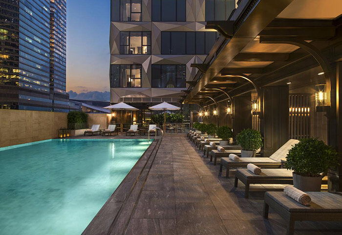 The St. Regis Hong Kong gay-friendly hotel pool. Lounge chairs line the pool deck. Luxury travel for gay men in Hong Kong.