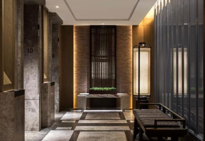 Hallway view in The St. Regis Hong Kong, a gay-friendly hotel. Features marble columns, patterned floors, and decorative lighting.