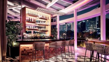 Bar at The St. Regis Mexico City, a gay-friendly hotel. City skyline view, stylish interior, bottle display, and modern design. Upscale travel.