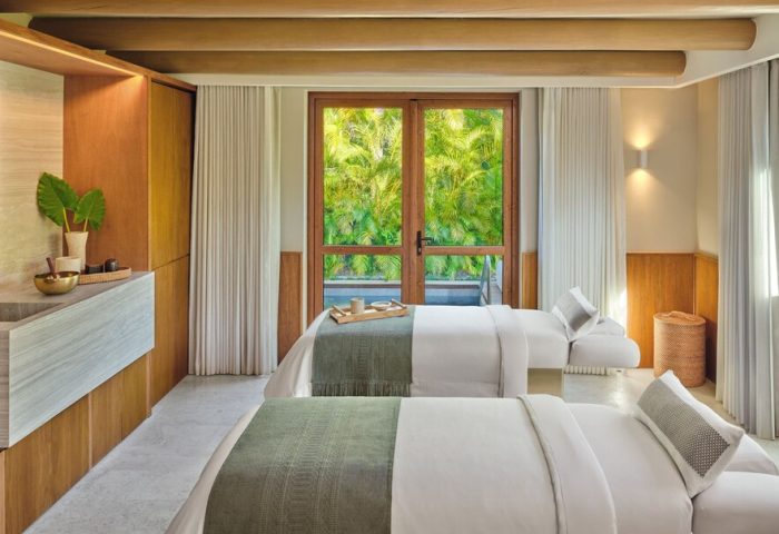 Gay-friendly hotel The St. Regis Punta Mita Resort spa. Two massage beds face a window with lush green view. Relaxing retreat.
