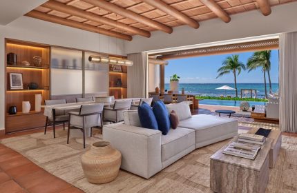 Interior view at The St. Regis Punta Mita Resort, a gay-friendly hotel. Living area with ocean view, pool, and palm trees. Luxury travel.
