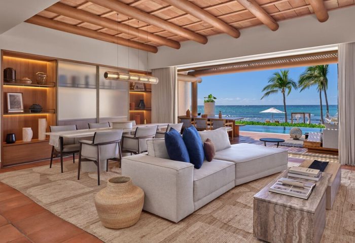 Interior view at The St. Regis Punta Mita Resort, a gay-friendly hotel. Living area with ocean view, pool, and palm trees. Luxury travel.