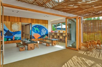 Playroom at The St. Regis Punta Mita Resort, a gay-friendly hotel. Kids' area with tables, benches, and colorful ocean-themed murals. Rattan ceiling.