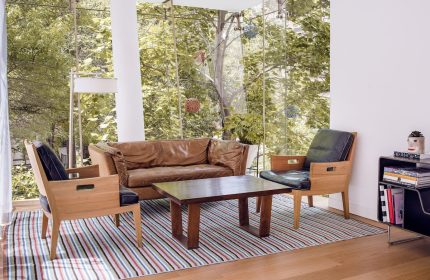 The Standard East Village: Gay-friendly hotel room with brown leather couch, chairs, table, striped rug, and floor-to-ceiling windows.