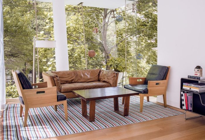 The Standard East Village: Gay-friendly hotel room with brown leather couch, chairs, table, striped rug, and floor-to-ceiling windows.