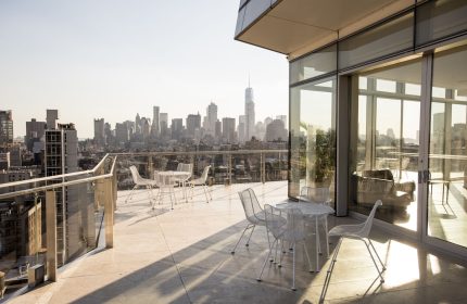 The Standard East Village gay-friendly hotel balcony view. New York City skyline with tables and chairs. Great spot for gay travelers.