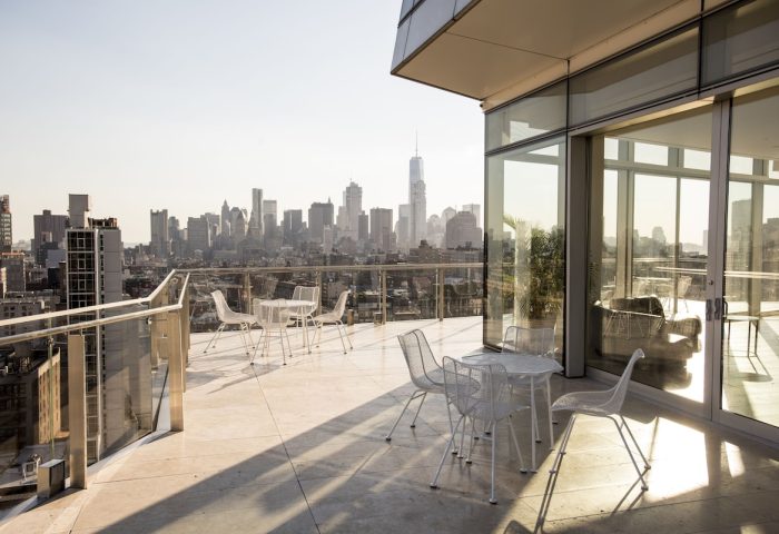 The Standard East Village gay-friendly hotel balcony view. New York City skyline with tables and chairs. Great spot for gay travelers.