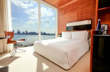 The Standard High Line New York hotel room. Gay-friendly hotel with skyline view. Modern design, white bedding, and Hudson River view.