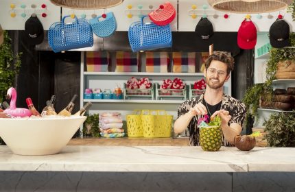 Man making pineapple cocktail at The Standard, High Line, New York. Gay-friendly hotel with colorful decor, bags, hats, and a flamingo ice bucket.