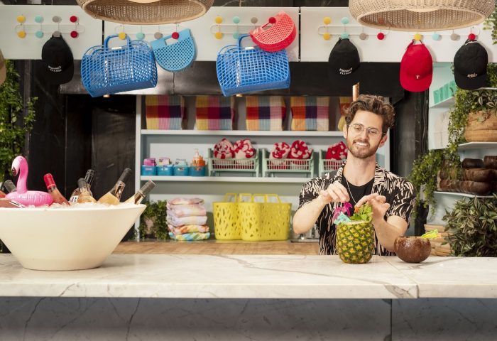 Man making pineapple cocktail at The Standard, High Line, New York. Gay-friendly hotel with colorful decor, bags, hats, and a flamingo ice bucket.