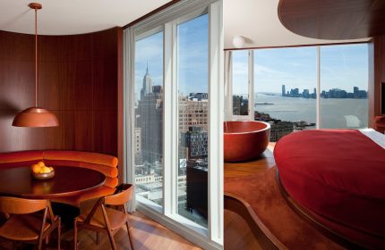 The Standard High Line New York interior. Gay-friendly hotel room with Empire State Building view, red round tub and bed, dining area.