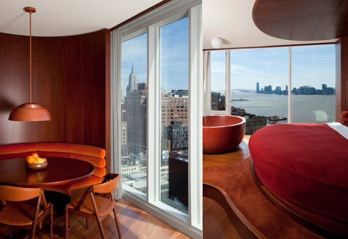 The Standard High Line New York interior. Gay-friendly hotel room with Empire State Building view, red round tub and bed, dining area.