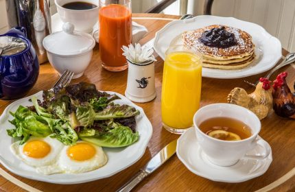 Breakfast at The Standard High Line New York, a gay-friendly hotel. Eggs, salad, pancakes, juice, and tea on a wooden table.