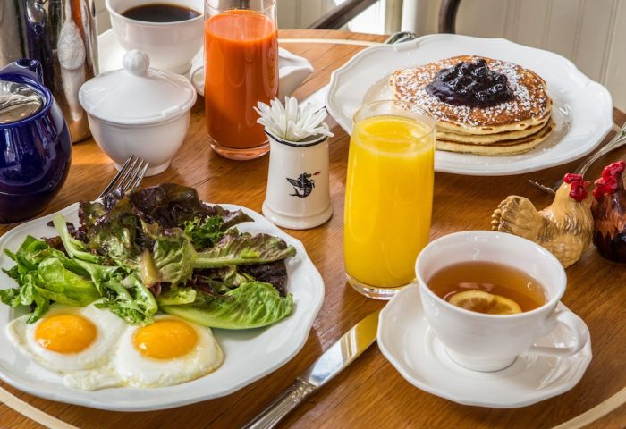 Breakfast at The Standard High Line New York, a gay-friendly hotel. Eggs, salad, pancakes, juice, and tea on a wooden table.