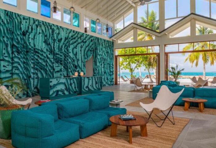 Lobby at The Standard, Huruvalhi Maldives, a gay-friendly hotel. Turquoise decor, comfy seating, and ocean views. Ideal gay travel destination.