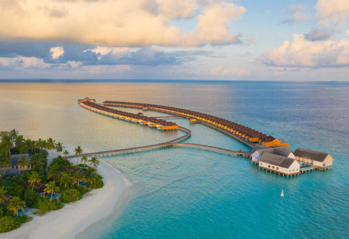 Aerial view of The Standard, Huruvalhi Maldives, a gay-friendly hotel. Overwater bungalows and turquoise waters. Tropical paradise.