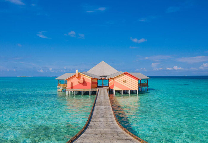 The Standard, Huruvalhi Maldives: Overwater bungalow at this gay-friendly hotel. Turquoise water, blue sky, and wooden walkway.