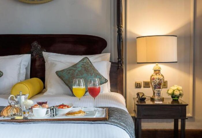 The Strand Yangon gay-friendly hotel room service. Breakfast in bed with juice, pastries, and fruit. Luxury travel in Yangon, Myanmar.