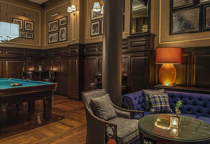The Strand Yangon gay-friendly hotel: Billiard room with pool table, sofa, and chairs. A luxurious space for travelers in Yangon, Myanmar.