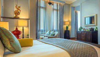 The Strand Yangon gay-friendly hotel room. Luxurious bed, sitting area, and elegant decor create a welcoming atmosphere for gay travelers.