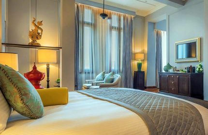 The Strand Yangon gay-friendly hotel room. Luxurious bed, sitting area, and elegant decor create a welcoming atmosphere for gay travelers.