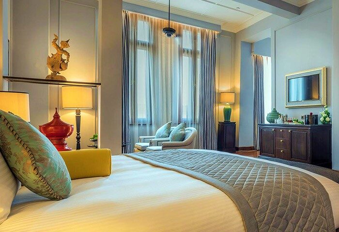 The Strand Yangon gay-friendly hotel room. Luxurious bed, sitting area, and elegant decor create a welcoming atmosphere for gay travelers.