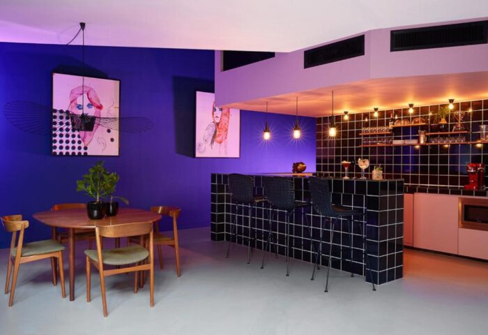 Interior of The Student Hotel Amsterdam City, a gay-friendly hotel. Features a bar, dining table, and modern art. Ideal for gay travelers.