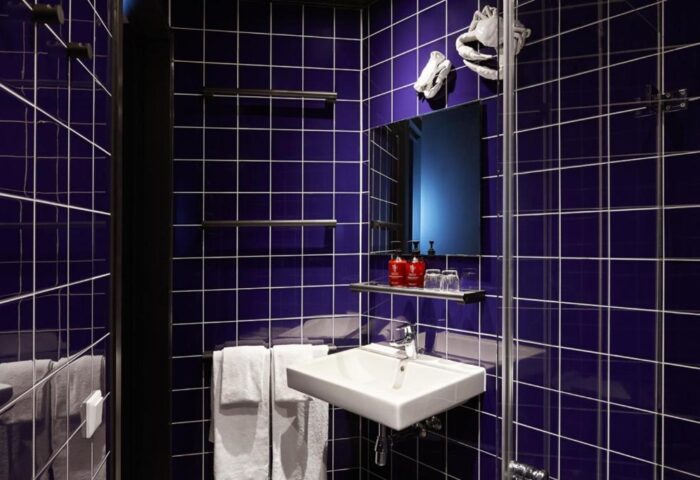 Bathroom at The Student Hotel Amsterdam City. Gay-friendly hotel with blue tiles, square sink, and modern decor. Amsterdam travel advice.