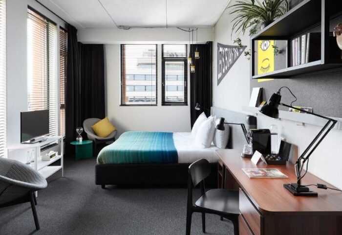 Student Hotel Amsterdam City room. A gay-friendly hotel with a bed, desk, chairs, and modern decor. Ideal for gay men's travel in Amsterdam.