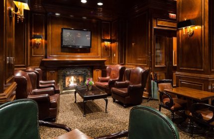 Gay-Friendly The Sutton Place Hotel Vancouver lounge. Leather chairs, fireplace, and wood paneling create a luxurious, welcoming ambiance.