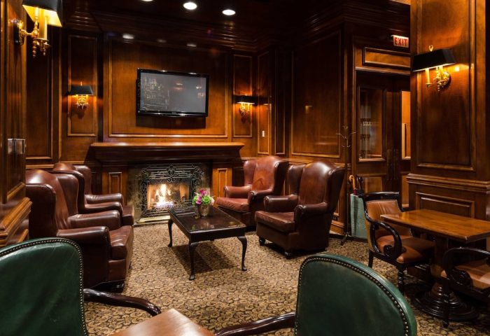 Gay-Friendly The Sutton Place Hotel Vancouver lounge. Leather chairs, fireplace, and wood paneling create a luxurious, welcoming ambiance.