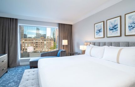 Sutton Place Hotel Vancouver room with city view. Gay-friendly hotel featuring modern decor, large windows, and comfortable chaise lounge.