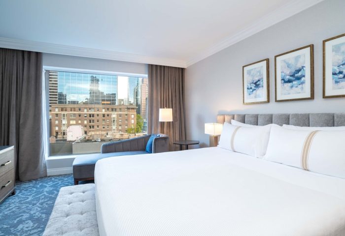 Sutton Place Hotel Vancouver room with city view. Gay-friendly hotel featuring modern decor, large windows, and comfortable chaise lounge.