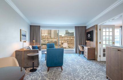 The Sutton Place Hotel Vancouver suite. Gay-friendly hotel room with city view, sofa, desk, and modern decor. Ideal for gay travel in Vancouver.