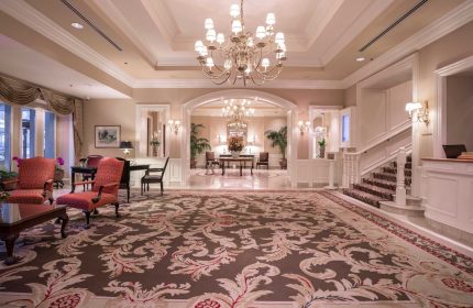The Sutton Place Hotel Vancouver lobby. Gay-friendly hotel with elegant decor, chandeliers, seating area, and staircase. Upscale travel.
