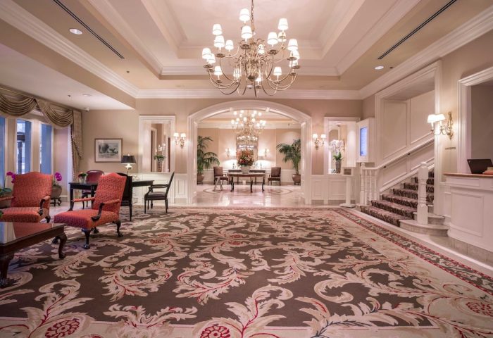 The Sutton Place Hotel Vancouver lobby. Gay-friendly hotel with elegant decor, chandeliers, seating area, and staircase. Upscale travel.