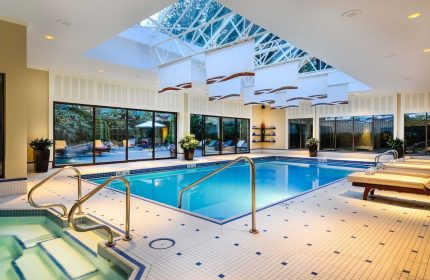 Indoor pool at The Sutton Place Hotel Vancouver, a gay-friendly hotel. Bright, with skylight, lounge chairs, and jacuzzi. Relaxing vacation.