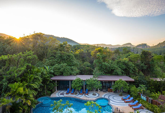 Gay-friendly The Tama Hotel pool & lounge area at sunrise. Lush green jungle backdrop. A serene getaway for gay travelers.